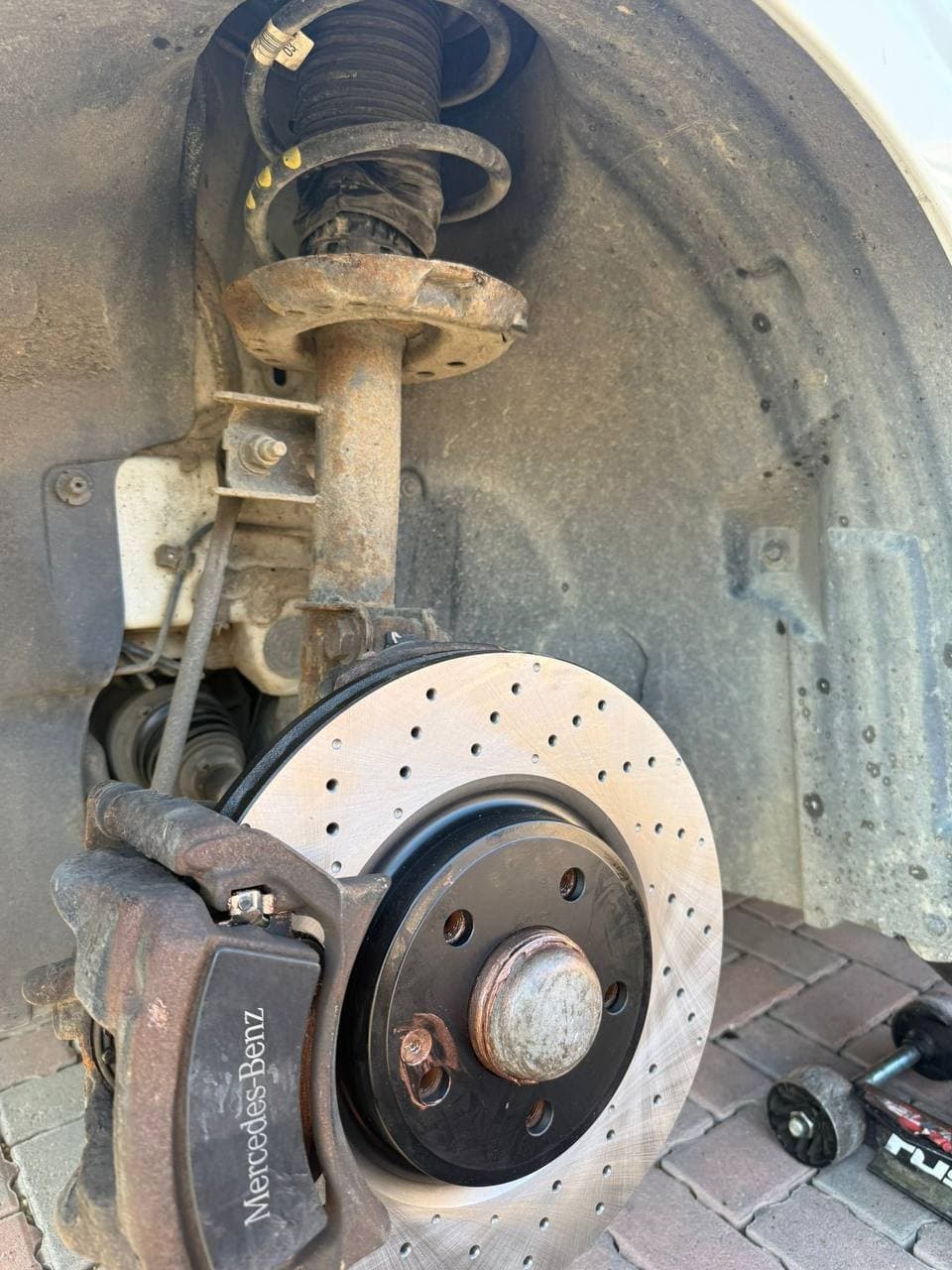 A cross drilled brake disc and caliper on the front of a Mercedes-Benz