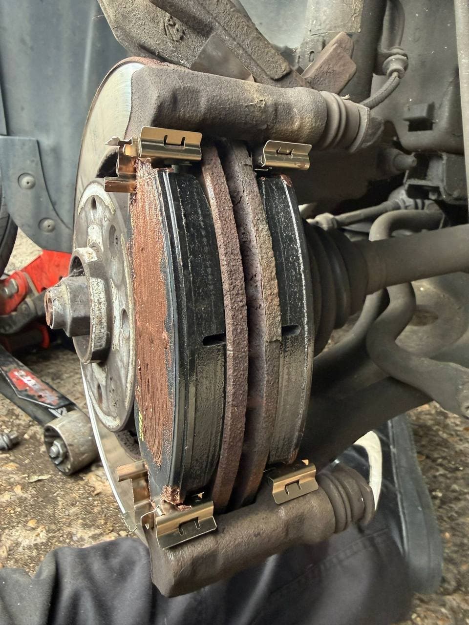 A scored brake disc and heavily worn pads still fitted to the hub