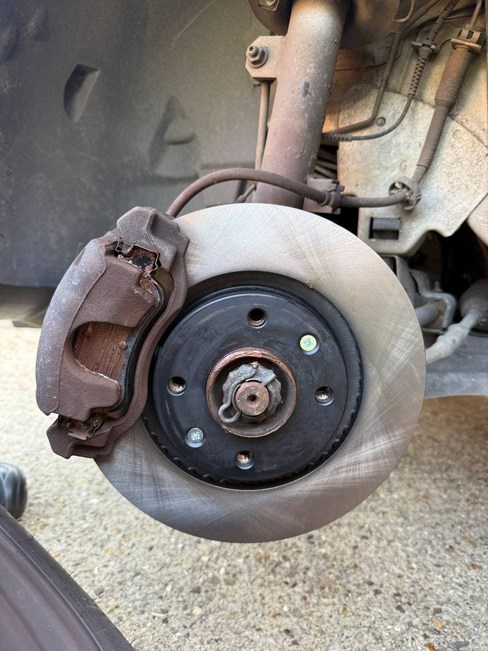 A brake disc and caliper on a front hub with the wheel removed