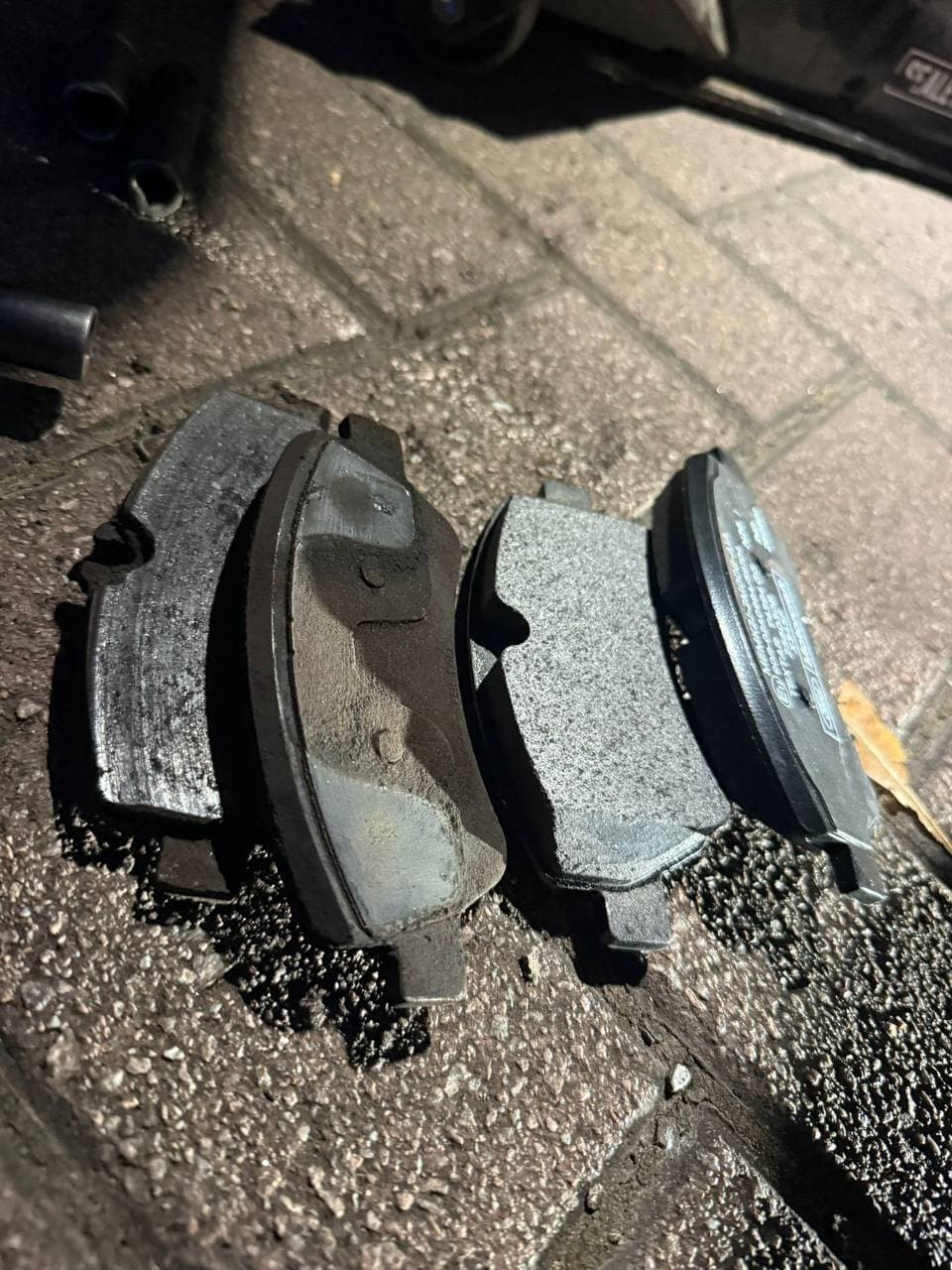 Four worn brake pads lined up on the ground after removal