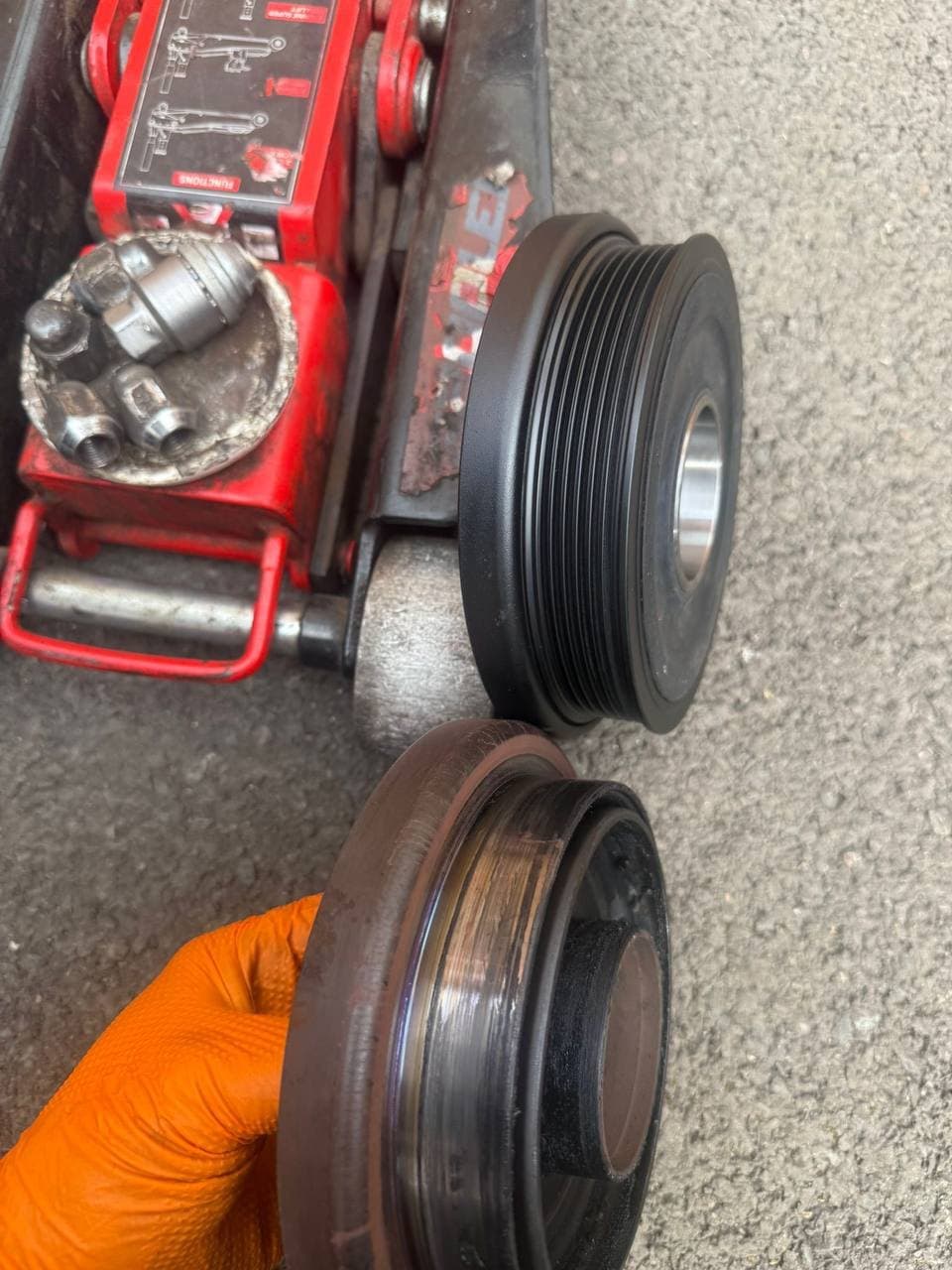 A new crankshaft pulley beside the worn one taken off the engine