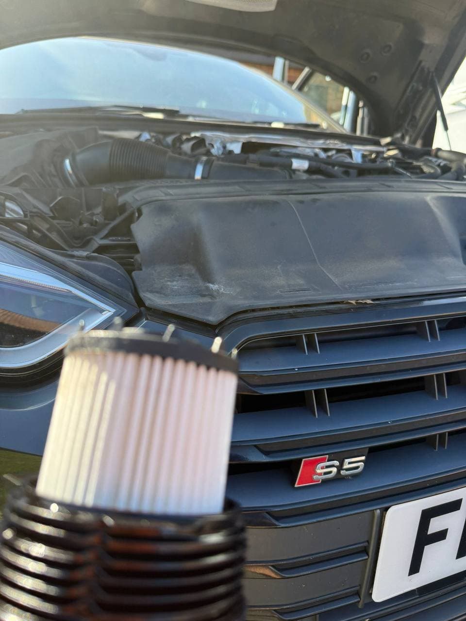 A clean oil filter element in its housing, held in front of an Audi S5