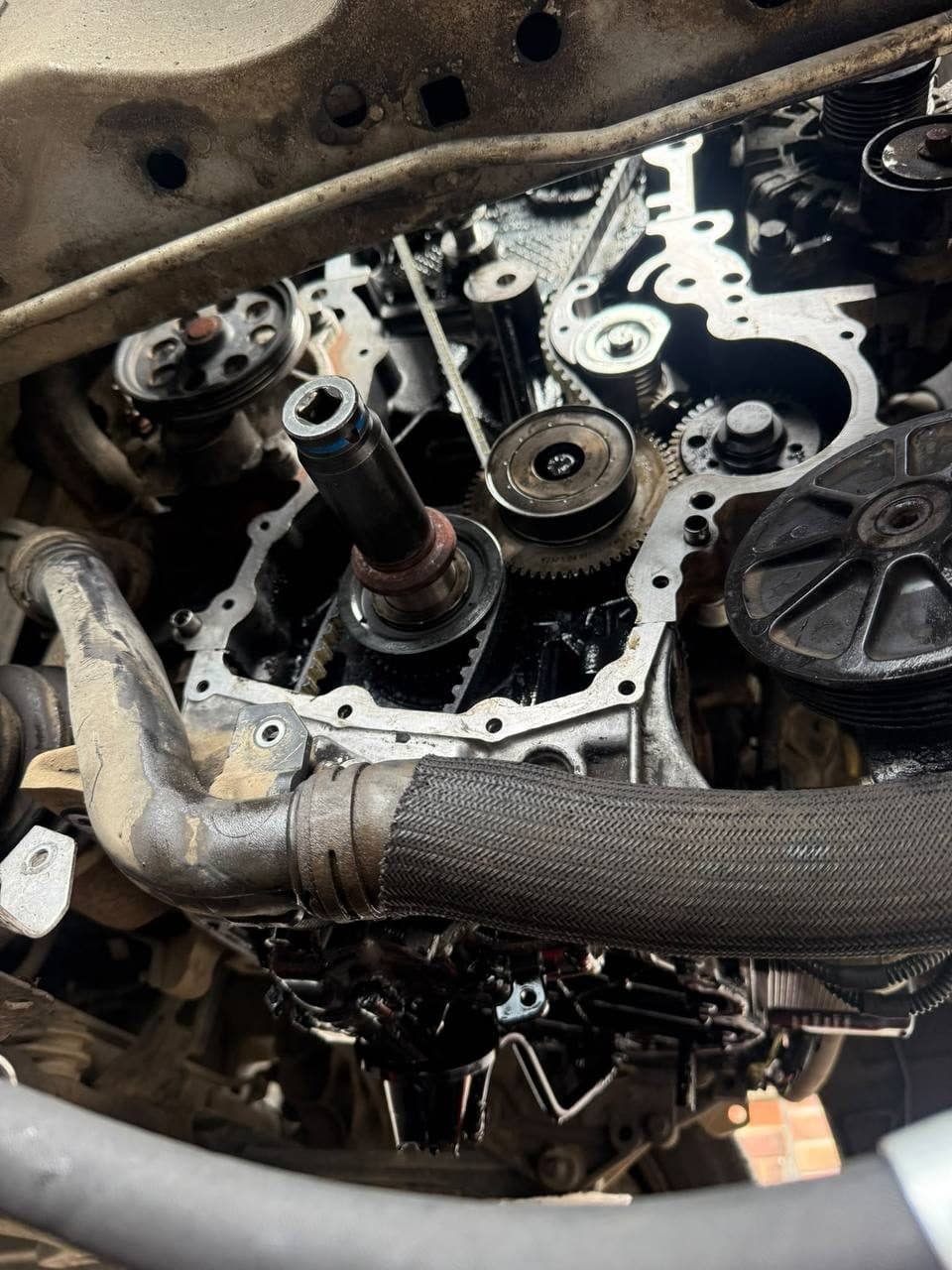 An engine with the timing cover off, showing the belt, gears and pulleys, with a socket on the crankshaft