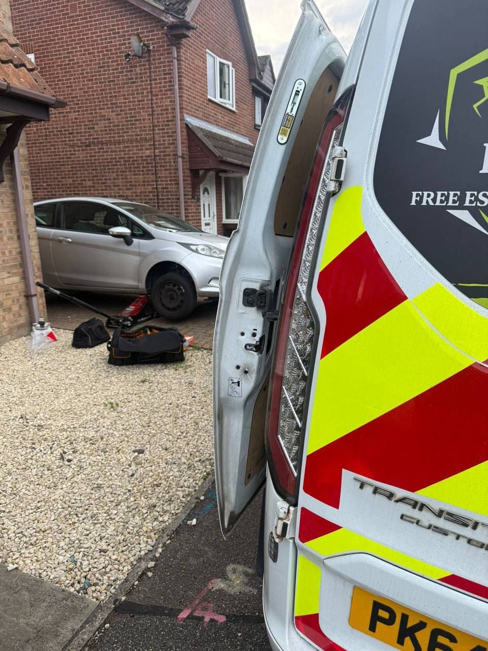 The EH Autos van with its rear doors open beside a car raised on a jack