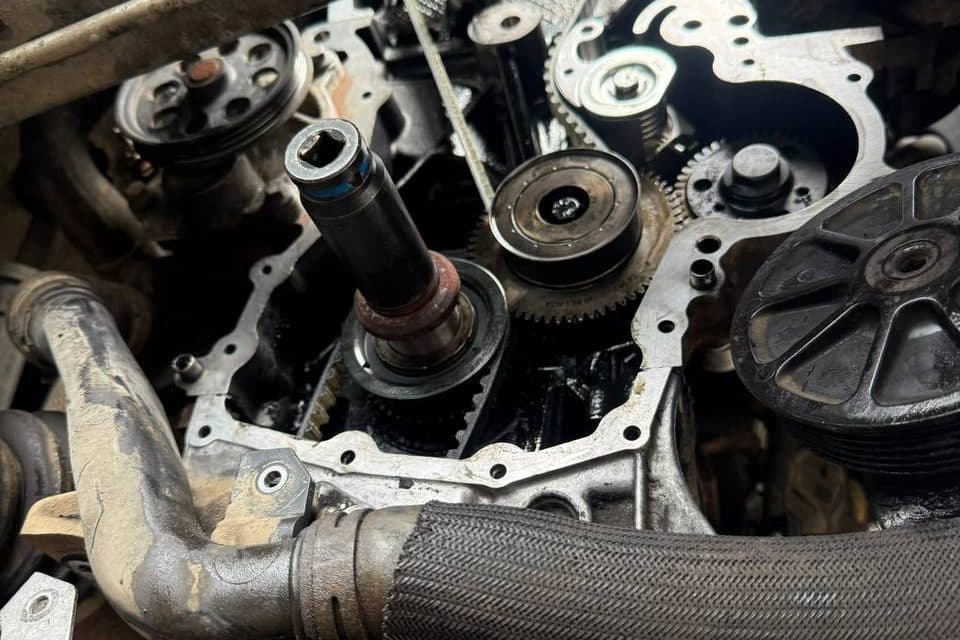 An engine with the timing cover off, showing the belt, gears and pulleys, with a socket on the crankshaft