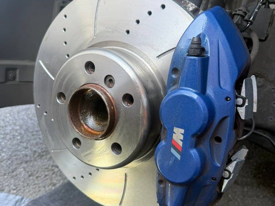 A cross drilled and grooved brake disc fitted behind an M Sport caliper