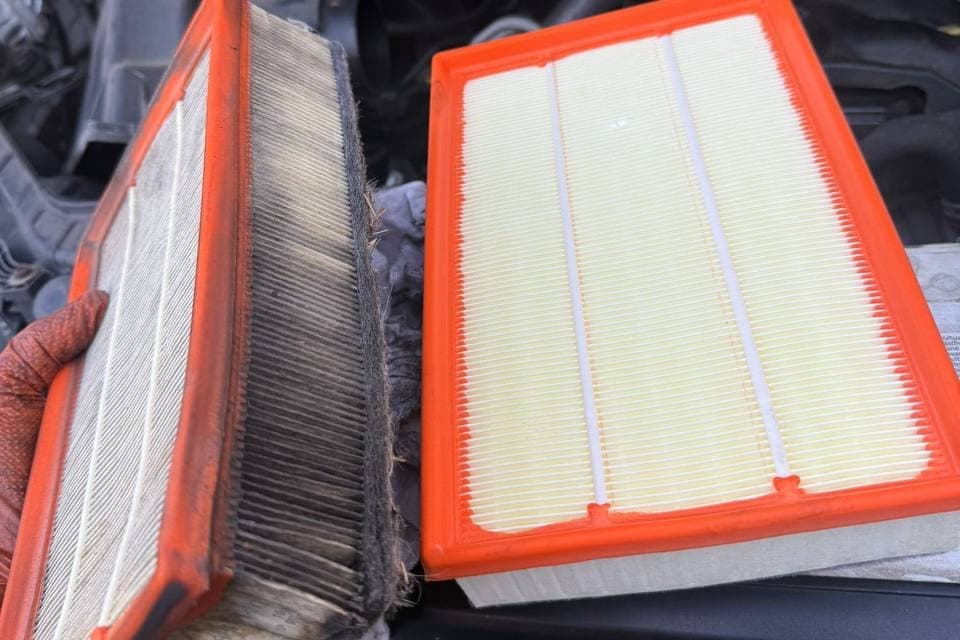 A dirt clogged air filter held beside the clean one replacing it